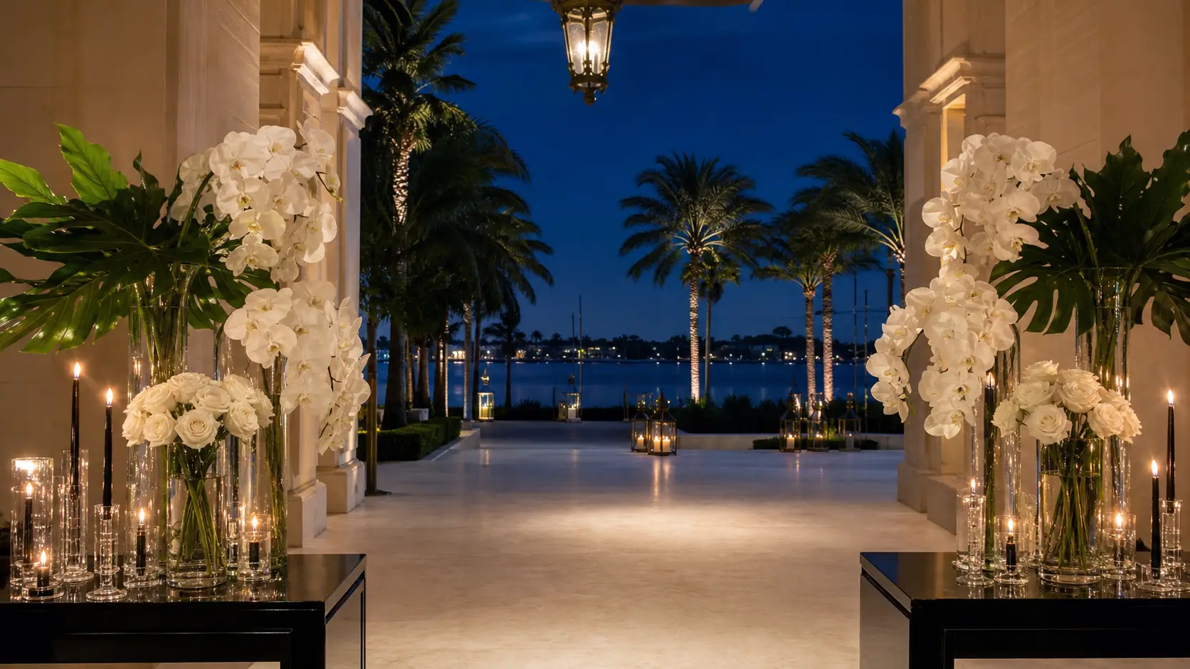 White orchids and candlelight framing an elegant waterfront entrance at night